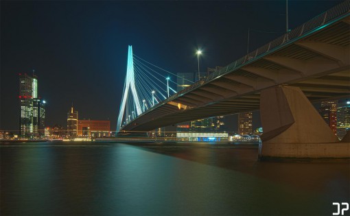 Avondfotografie van de Erasmusbrug in Rotterdam, en de skyline van de Wilhelminapier, vanaf de overzijde van de Nieuwe Maas.